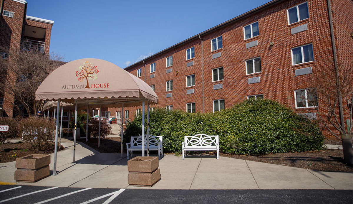 A building exterior featuring a patio with several chairs arranged for outdoor seating.