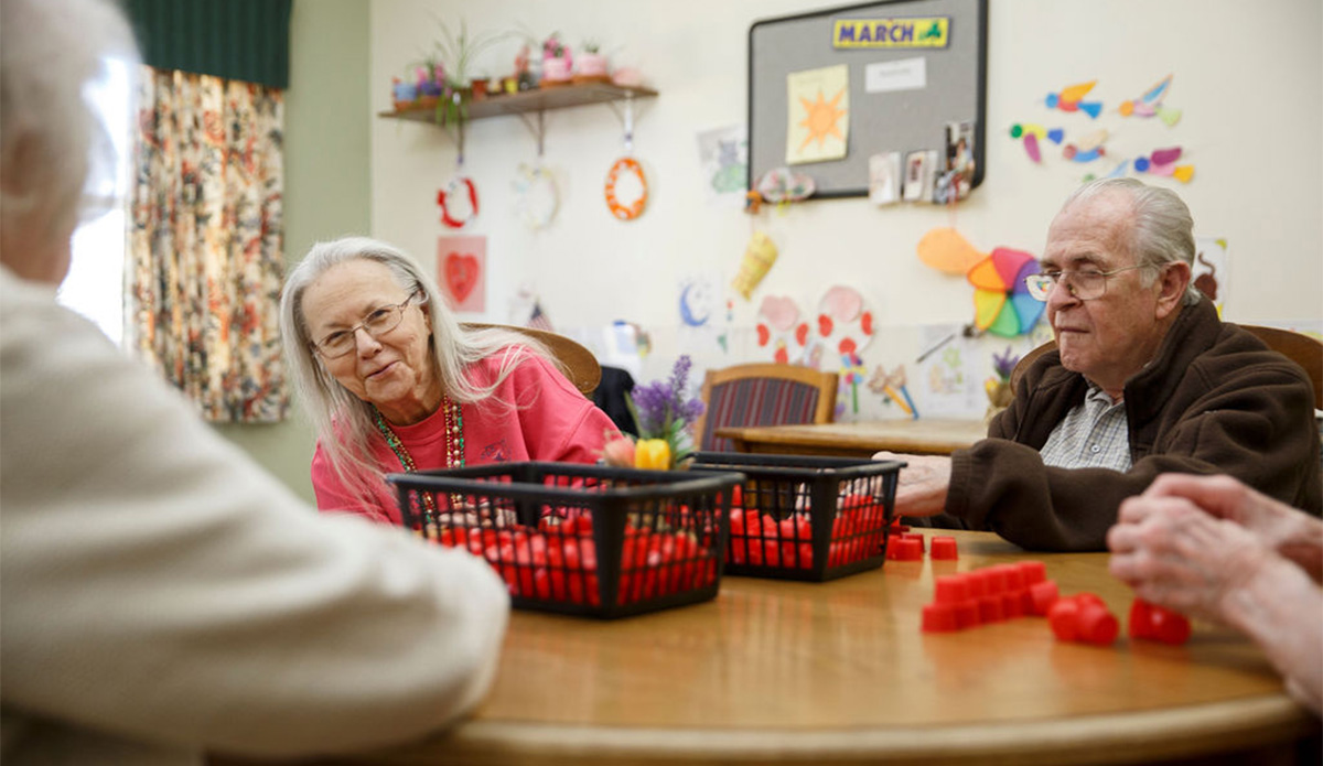 An elderly couple joyfully playing dominoes together at a table, sharing smiles and laughter.